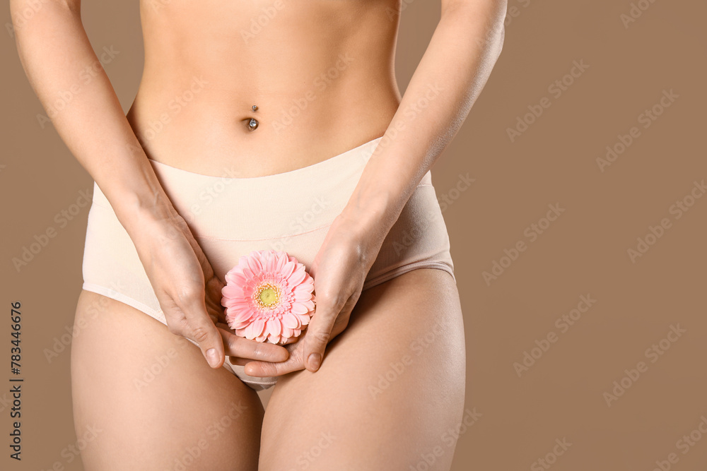 Young woman in panties with beautiful pink flower on brown background Young woman in panties with beautiful pink flower on brown background