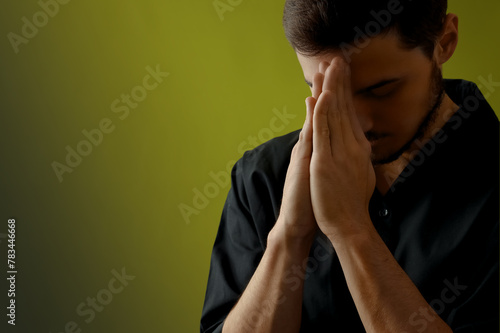 Young man praying on dark c...