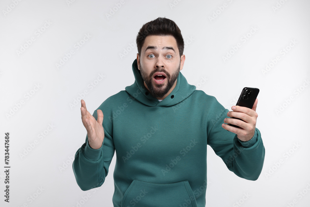 Shocked young man using smartphone on white background Shocked young man using smartphone on white background