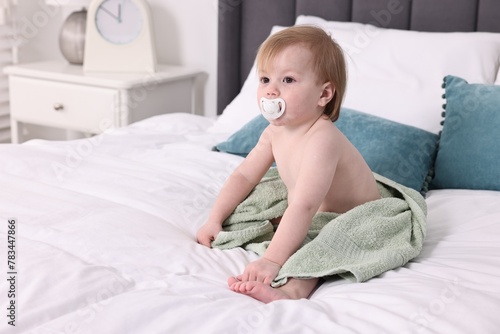 Cute little baby with towel after bathing on bed, space for text