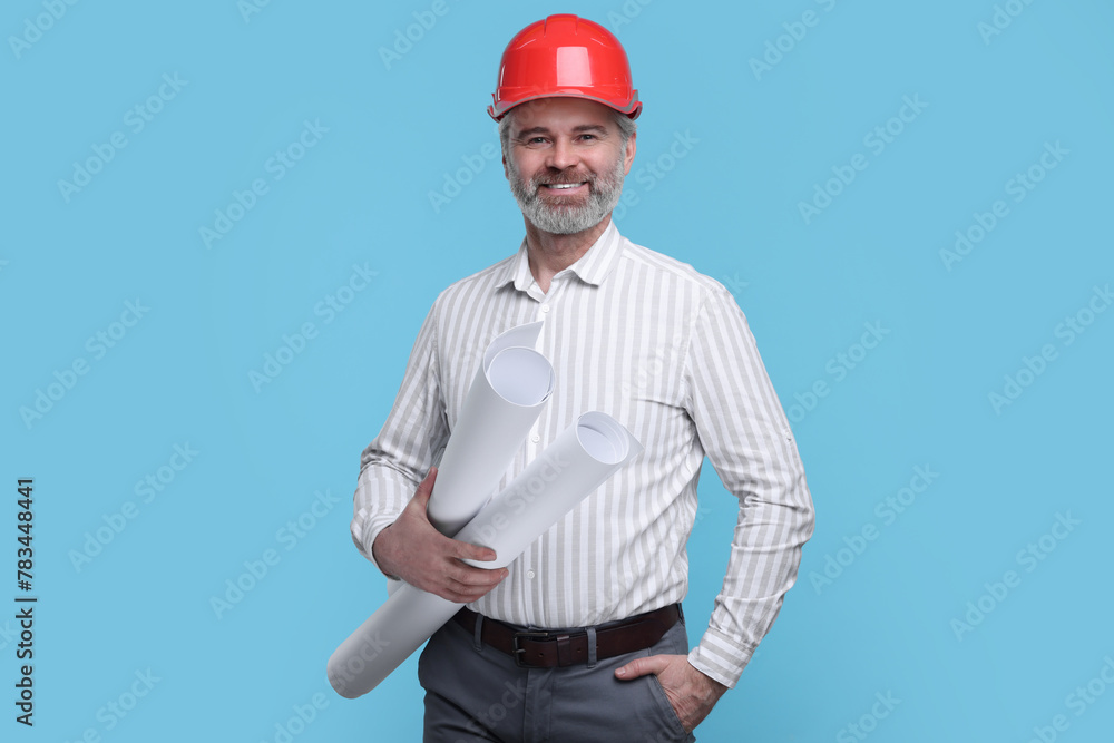 Architect in hard hat holding drafts on light blue background Architect in hard hat holding drafts on light blue background