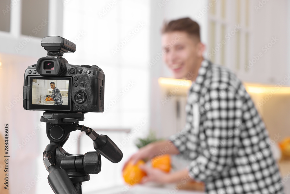 Food blogger recording video in kitchen, focus on camera