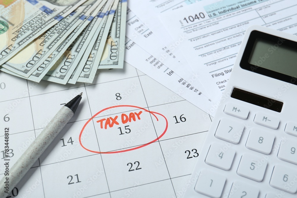 Calendar with date reminder about tax day, documents, pen, calculator and money, above view Calendar with date reminder about tax day, documents, pen, calculator and money, above view