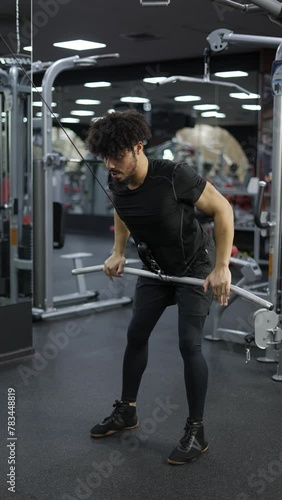 Young man exercising on lateral pull at gym for the back mucles photo