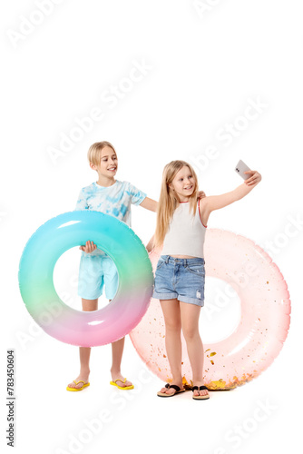 Cute little kids with inflatable rings taking selfie on white background
