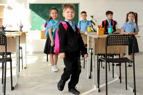 Cute little schoolboy running in classroom. School holidays concept