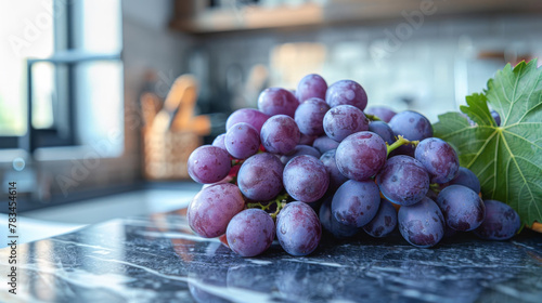A bunch of freshly picked purple grapes on a granite kitchen counter top and illuminated by window light.