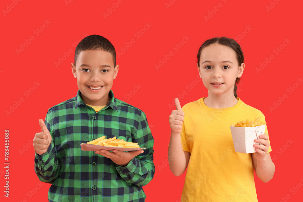 Happy little children with french fries showing thumbs-up gesture on red background Happy little children with french fries showing thumbs-up gesture on red background