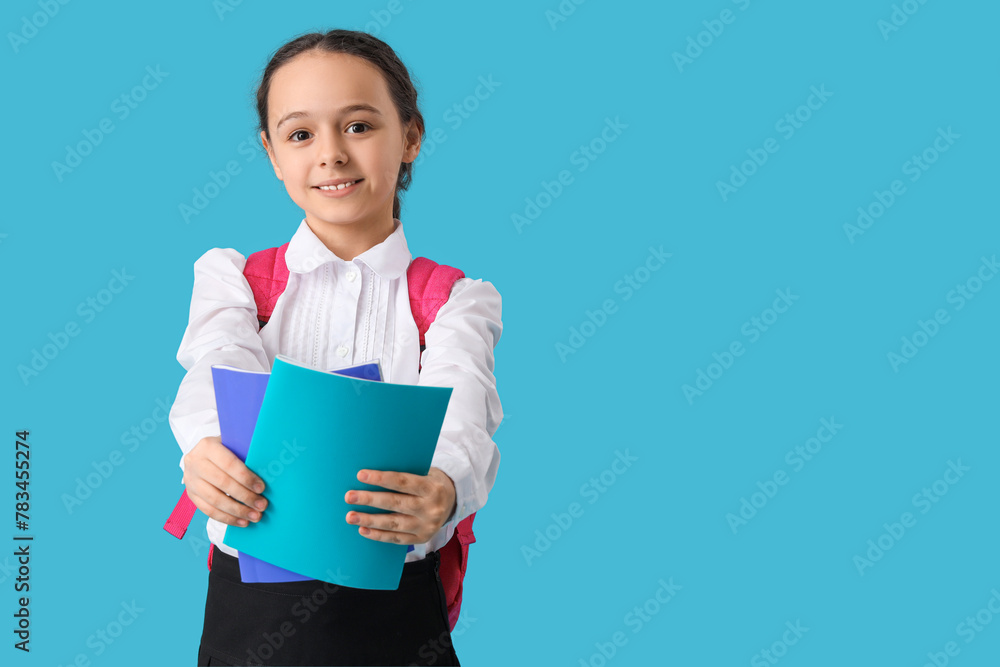 Happy little schoolgirl with backpack and notebooks on blue background Happy little schoolgirl with backpack and notebooks on blue background