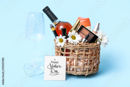 Gift basket with decorative cosmetics, bottle of wine and glass for Mother's Day celebration on color background