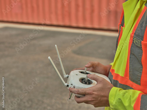 Engineer or  worker piloting drone at ontainer cargo ship at shipping port. video surveillance or industrial inspection photo