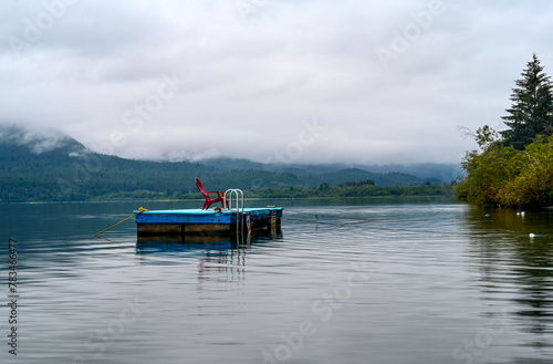 Relaxing floating pier with red chair on lake with mist