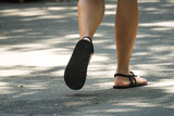 A woman is walking on a sidewalk wearing black sandals