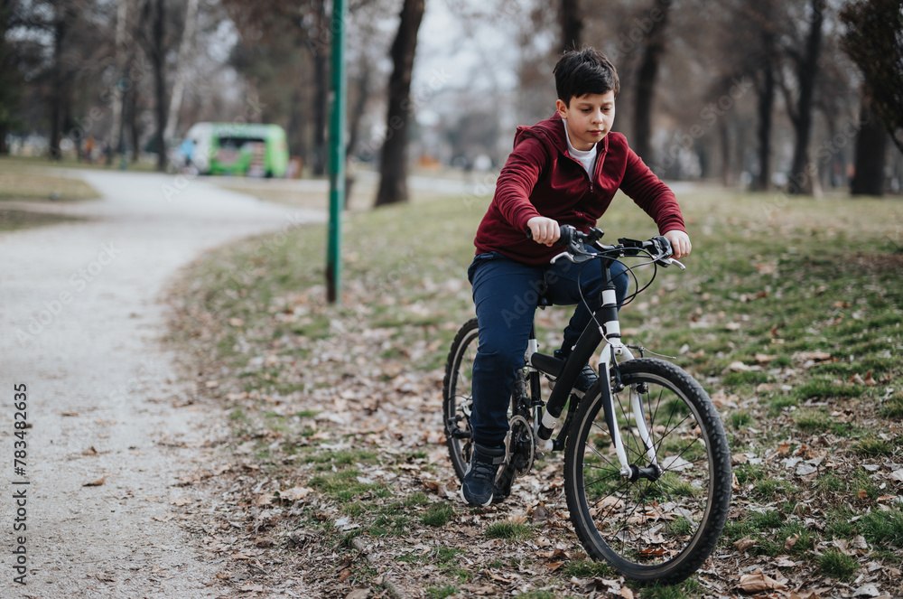 Carefree young boy riding his bicycle in an urban park, experiencing the joy and freedom of childhood outdoors. Carefree young boy riding his bicycle in an urban park, experiencing the joy and freedom of childhood outdoors.