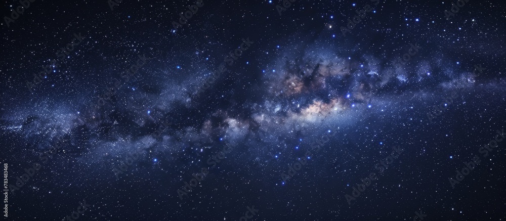 Obraz premium The Milky Way, a stunning band of stars and planets, is visible in the dark expanse of the night sky