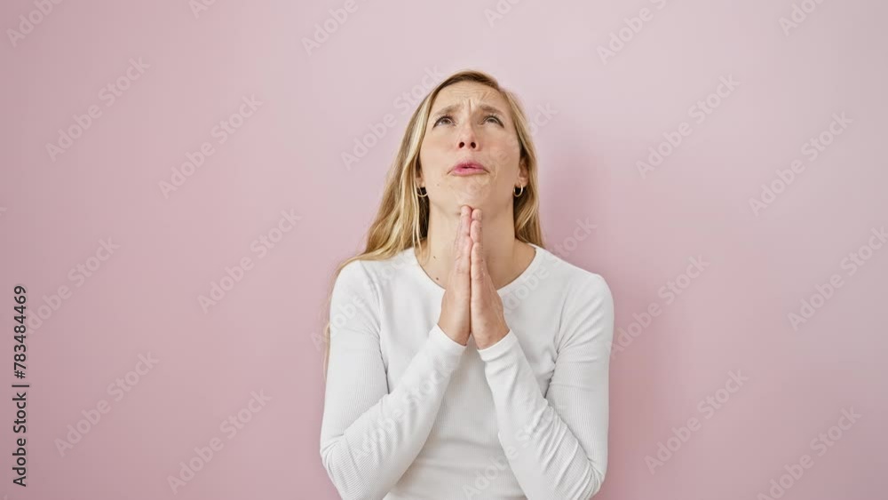 Desperate young blonde woman begs for forgiveness, praying with hands together, emotion etched on her face. standing alone over pink isolated background Desperate young blonde woman begs for forgiveness, praying with hands together, emotion etched on her face. standing alone over pink isolated background