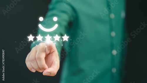 Customer hand touching the virtual screen on happy smile face icon to give satisfaction in service. Concept of assessment testimonial customer service and feedback, Opinion rating very impressed. © ParinPIX