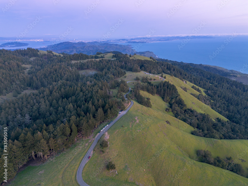 Arial shot of a road in the mountains with ocean on right and forest on left Arial shot of a road in the mountains with ocean on right and forest on left