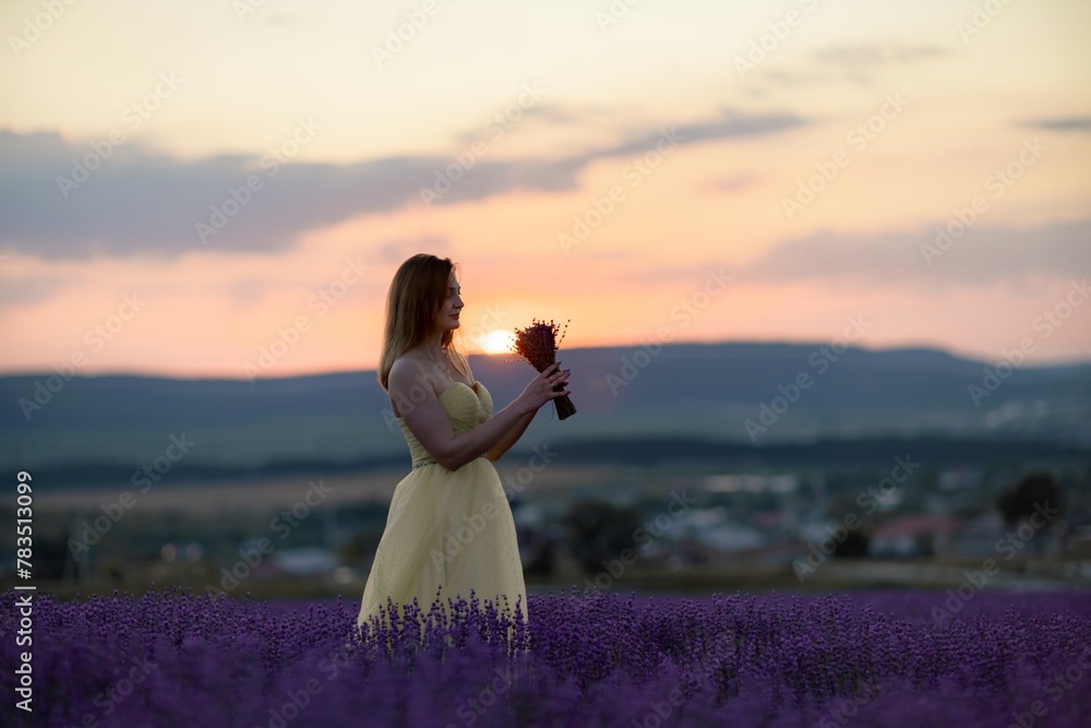 Woman poses in lavender field at sunset. Happy woman in yellow dress holds lavender bouquet. Aromatherapy concept, lavender oil, photo session in lavender Woman poses in lavender field at sunset. Happy woman in yellow dress holds lavender bouquet. Aromatherapy concept, lavender oil, photo session in lavender