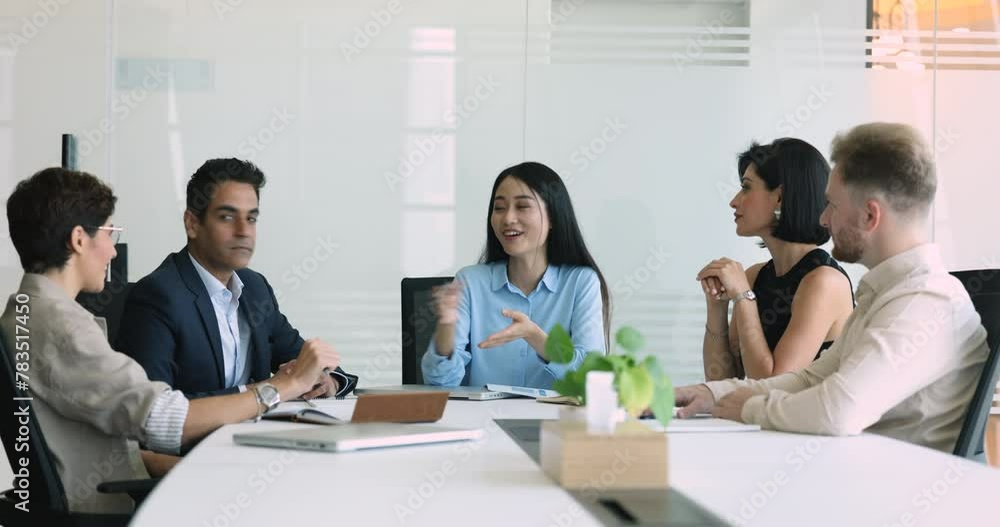 Positive beautiful young Asian team leader woman talking to multiethnic colleagues, explaining creative idea to diverse team, speaking at large meeting table, enjoying teamwork communication Positive beautiful young Asian team leader woman talking to multiethnic colleagues, explaining creative idea to diverse team, speaking at large meeting table, enjoying teamwork communication
