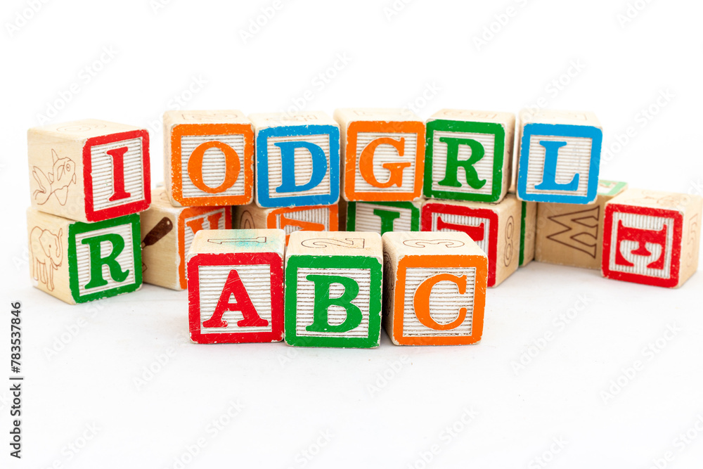 Multi-colored wooden letter blocks with ABC alphabets are selective focused isolated on white wood background Multi-colored wooden letter blocks with ABC alphabets are selective focused isolated on white wood background