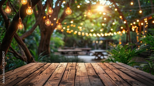 Empty wood table for product display with decorative outdoor string lights hanging on tree at night time. photo