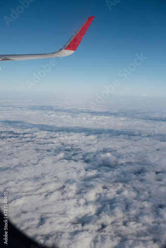 View from window of an airplane flying above the clouds (ID: 783540405)
