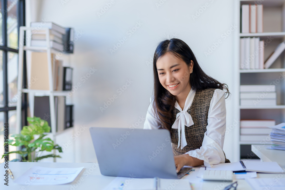 Focused young professional working on a laptop with financial reports. Organized and diligent work approach concept Focused young professional working on a laptop with financial reports. Organized and diligent work approach concept