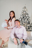 Man and woman in pink clothes with a gift at the Christmas tree. 