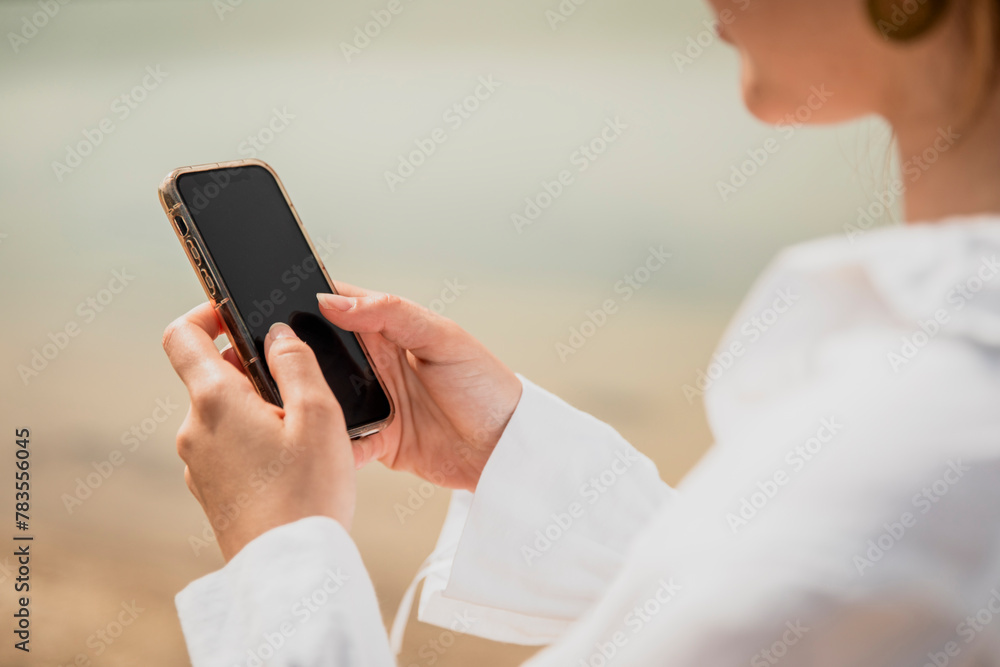 Close-up of a girl's hands typing on her smartphone next to a lake