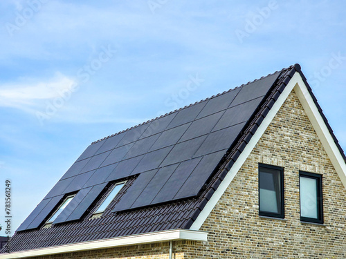New house with black solar panels on the roof against a sunny sky ,new building with black solar panels. Zonnepanelen, Zonne energie, Translation: Solar panel, Sun Energy, Dutch Suburban area 