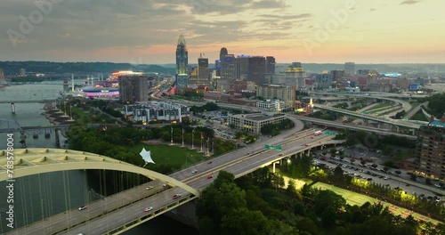 Downtown district of Cincinnati city in Ohio, USA at sunset with driving cars traffic on Daniel Carter Beard Bridge and brightly illuminated high skyscraper buildings. American travel destination photo