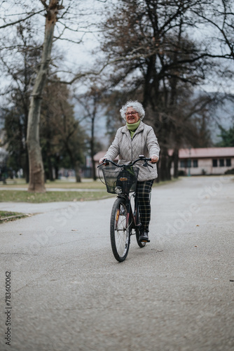 A joyful mature woman with gray hair cycling and smiling in a tranquil park setting, showcasing an active retirement lifestyle.