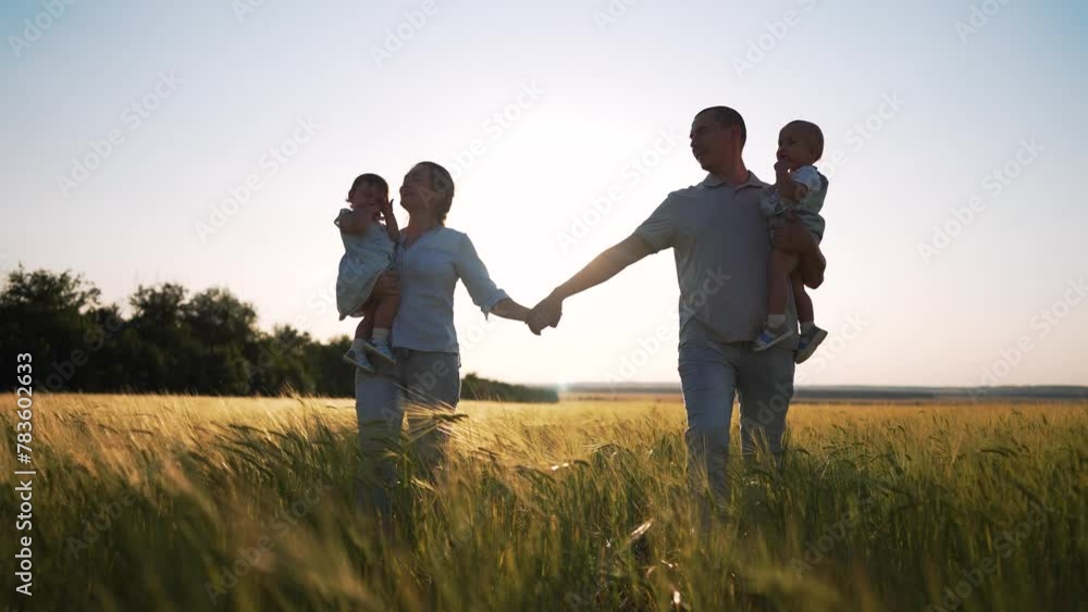 Silhouette of young happy family in wheat field walk at sunset in summer. Happy family concept.An active family of parents with toddlers walks in wheat field at sunset.Hiking in the countryside picnic Silhouette of young happy family in wheat field walk at sunset in summer. Happy family concept.An active family of parents with toddlers walks in wheat field at sunset.Hiking in the countryside picnic
