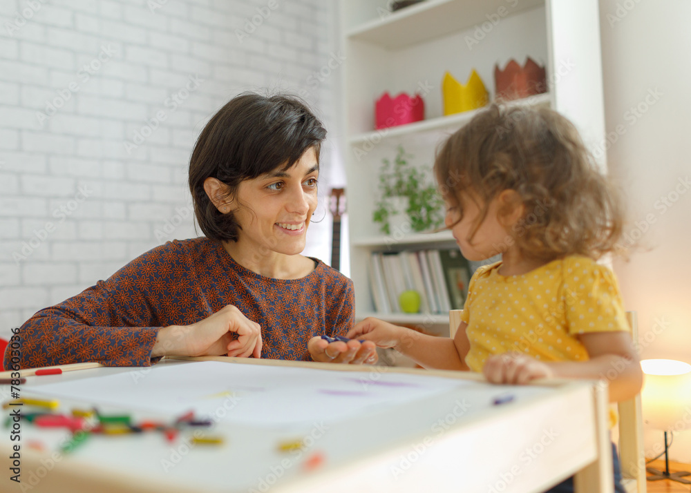 Fototapeta premium Mother and daughter sitting on the table and drawing. Learning with kids concept
