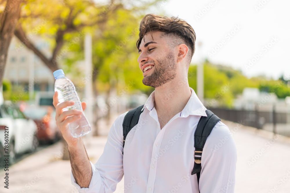 Young handsome man with a bottle of water at outdoors with happy expression Young handsome man with a bottle of water at outdoors with happy expression