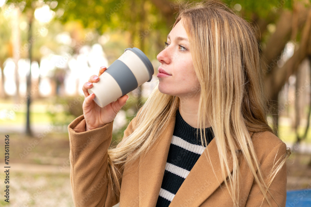 Young pretty blonde woman holding a take away coffee at outdoors Young pretty blonde woman holding a take away coffee at outdoors