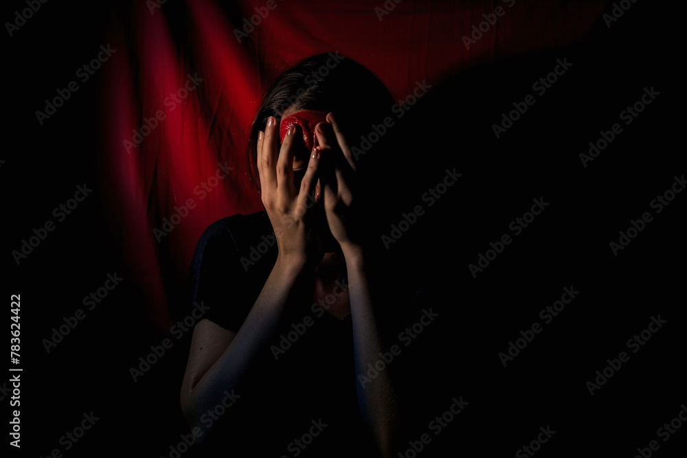 Person in despair with hands on face in dark, theatrical setting. Emotional pain and drama concept. Design for theatrical posters and mental health awareness. Person in despair with hands on face in dark, theatrical setting. Emotional pain and drama concept. Design for theatrical posters and mental health awareness.