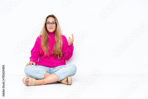 Young caucasian woman sitting on the floor isolated on white background pointing with the index finger a great idea