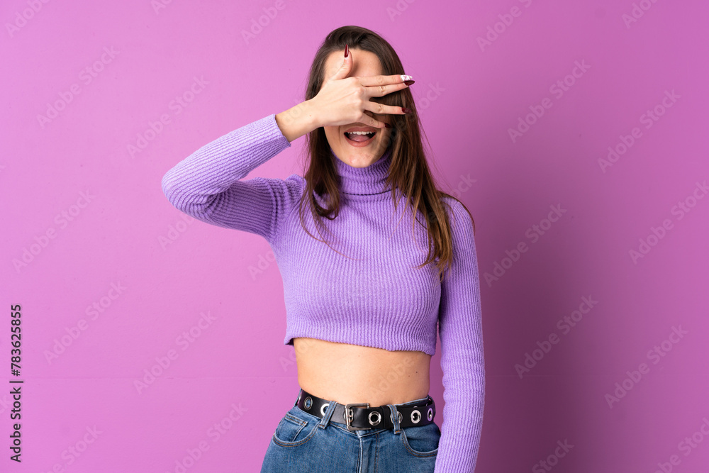 Young woman over isolated purple background covering eyes by hands and smiling Young woman over isolated purple background covering eyes by hands and smiling