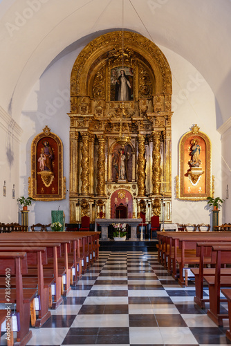 The vertical frame captures the opulent golden altar of Puig de Missa church in Santa Eulalia, Ibiza, surrounded by intricately carved religious figures