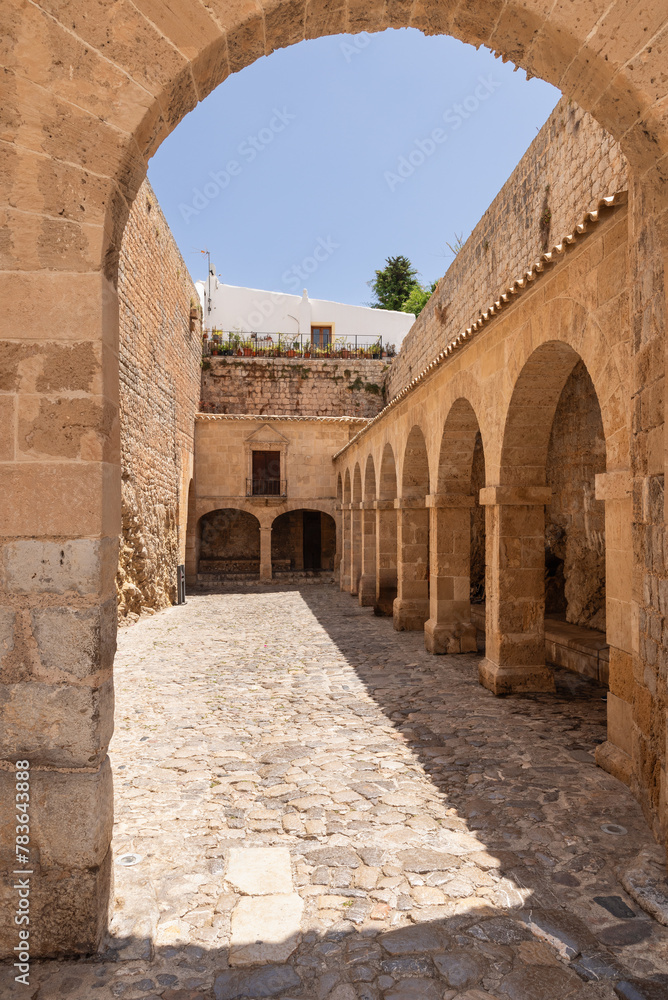 Sunlight dapples the cobbled courtyard of Almudaina Castle, highlighting the symmetry of its stone arches and inviting entryway in the heart of Eivissa town in Ibiza