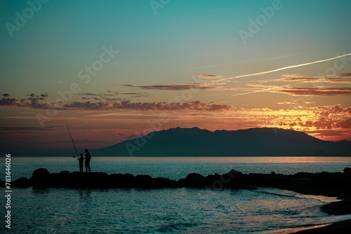 Silhouette of a fishermen on the shore during the sunset