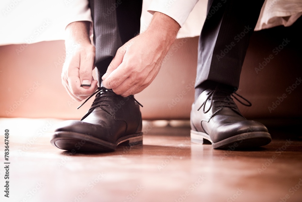 Closeup of hands of groom tying shoelaces on shoes - obrazy, fototapety, plakaty 