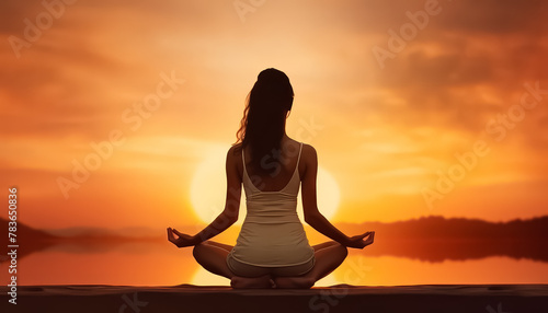 A woman is standing on a rock by the ocean, with her arms outstretched