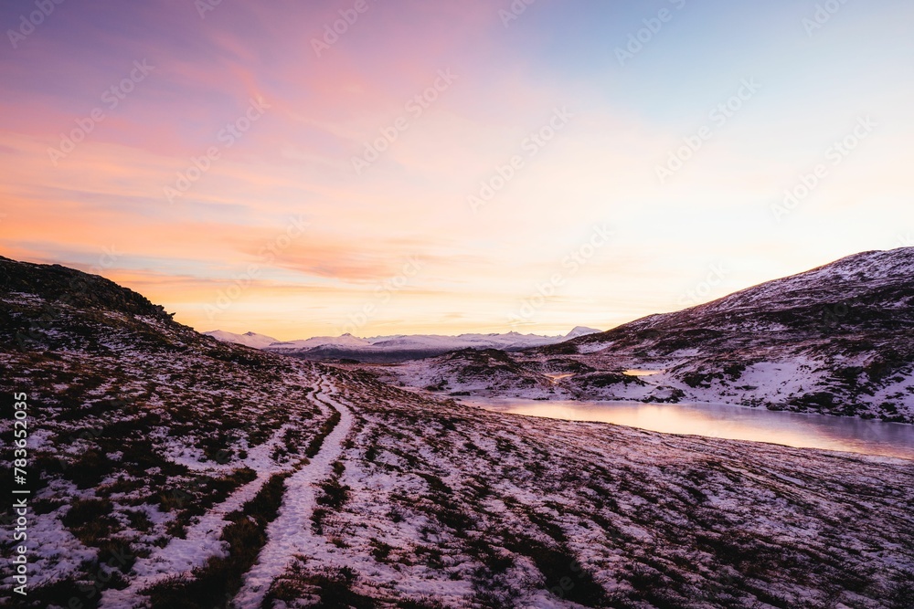 Fototapeta premium Rocky mountains covered with snow during scenic pink sunset, Tromso, Norway