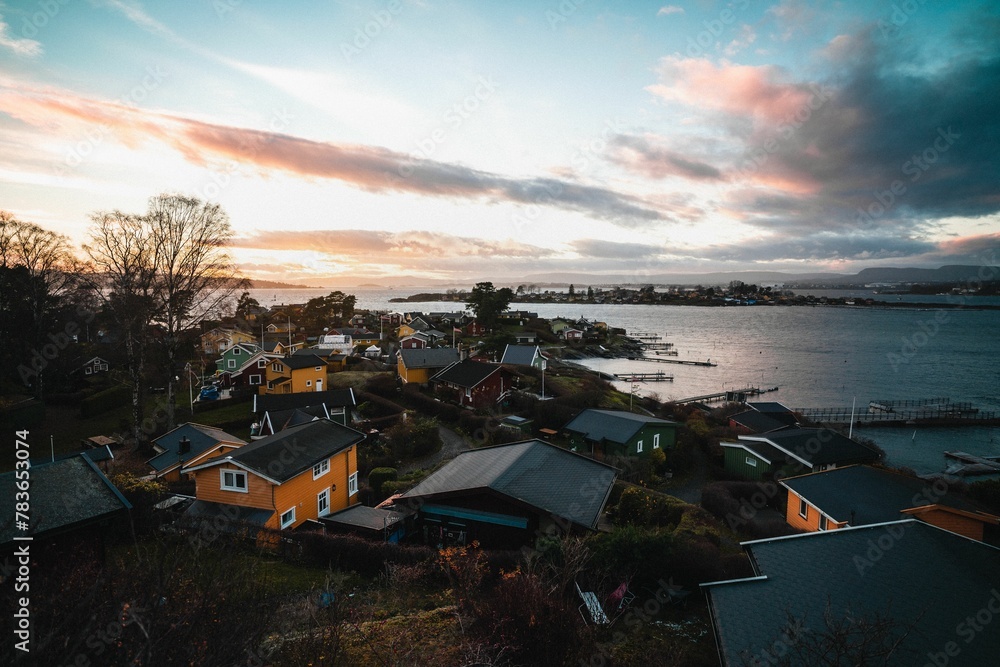 Aerial scenic view of lakeside houses in a village under pink and blue cloudy sunset sky