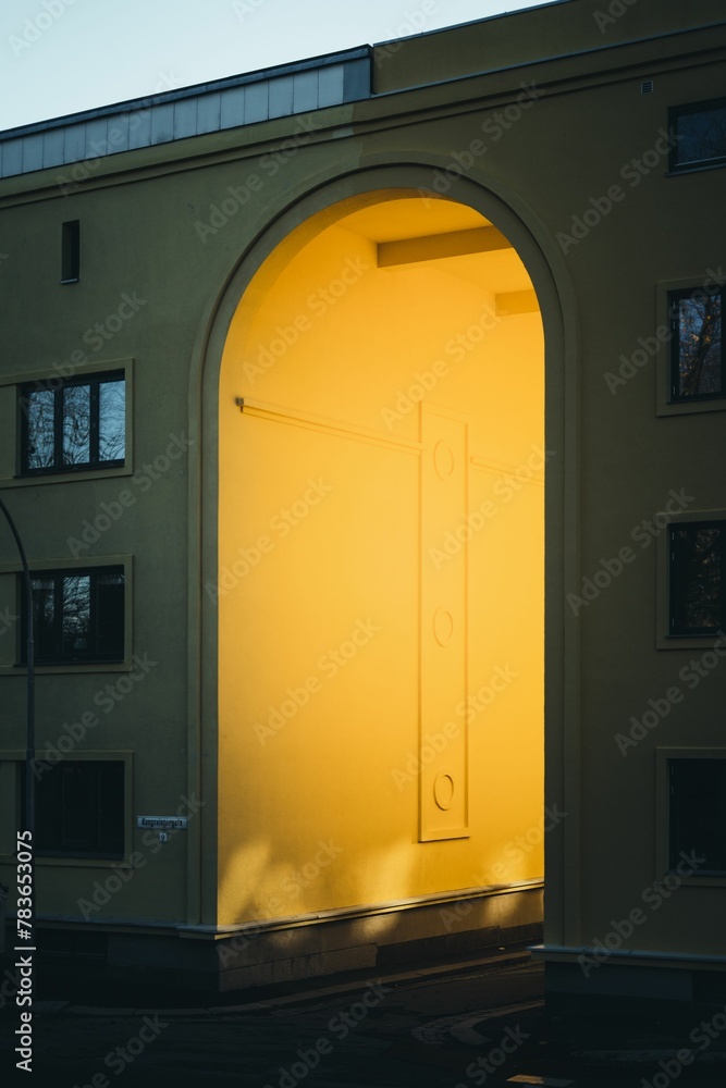 Vertical shot of arch alleyway entrance of a building with light coming from inside
