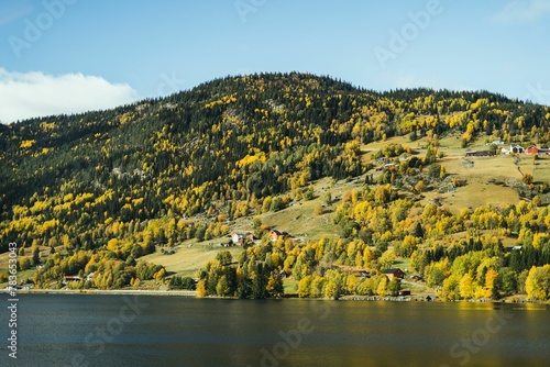 Scenic landscape of a lake with green and yellow mountain forests and houses photo