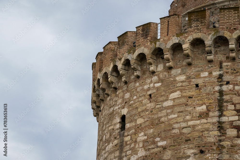 Closeup shot of a part of an old stone tower with blue sky in the background